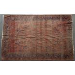 An early 20th century Sarouk red ground rug with a banded border and stylised foliate decoration,