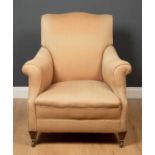 A cream upholstered armchair, with short square tapering front legs terminating in brass casters and