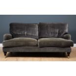 A contemporary grey upholstered sofa with turned tapering front legs terminating in brass casters,