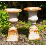 A pair of white painted cast iron small size campana urns on spreading plinth bases, each urn and