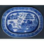 An 18th Century willow pattern blue & white meat platter, decorated with a rural scene and two