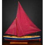 A model sailing boat on stand, the blue and red painted hull constructed from various woods and