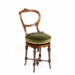 A late Victorian spoon back walnut revolving music chair with foliate carved cresting and