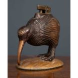 A 1950's gilt metal table lighter in the form of a Kiwi, possibly made in Japan, on carved wooden