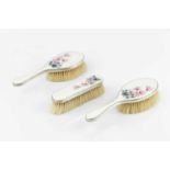 A pair of silver and enamel backed hair brushes, and a matching clothes brush, the ivory guilloche