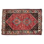 Red ground rug Afghanistan with shaped central panel with two medallions and with a stylised border,