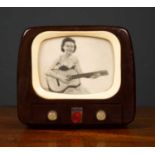 A 1950's Bakelite TV wind-up music box, the screen depicting a lady strumming a guitar, 12cm wide