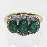 An 18 carat gold emerald and diamond triple cluster ring,