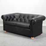 A modern black upholstered chesterfield sofa,