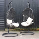 A pair of rattan hanging garden chairs, with loose cushions