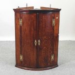 A George III oak bow front hanging corner cabinet