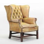 A Georgian style leather upholstered wing armchair