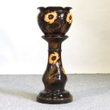 An early 20th century brown glazed pottery jardinière on stand