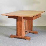 An Art Deco light oak draw leaf dining table