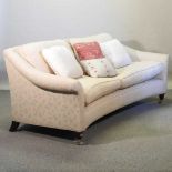 A modern cream upholstered curved three seat sofa