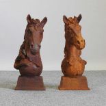 A pair of rusted metal horse head gate finials
