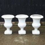 A set of three white painted garden urns