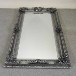 An ornate silver painted wall mirror