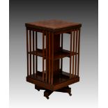 An Edwardian walnut revolving bookcase, two tier, with slatted sides, on an x-shaped base with