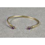 A 9ct gold, amethyst and diamond flexible torq style bangle, the terminals each set with a single