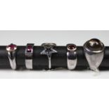 A collection of five silver rings set with various gemstones, compising of three set with rubies;