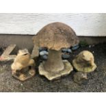 A composite stone toadstool and three garden frogs.,