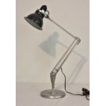 A modern anglepoise lamp, in grey, circular base.