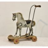 A late 19th to early 20th century gesso painted and carved pull-along toy horse, dapple grey, real