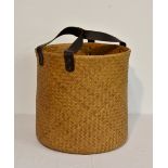 A woven laundry basket with leather strap handles.