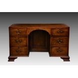 An early Georgian style walnut double pedestal desk, c.1920, the cross banded top over an arched