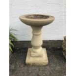 A sandstone style bird bath, of typical form with central column, raised on stepped square base,