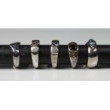 A collection of five silver rings set with various gemstones, comprising of blue topaz; two set with