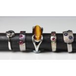 A collection of five silver rings set with various gemstones, comprising of tiger's eye; pink