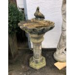 A large composite stone bird bath, having central column, raising to flower head shaped bath with