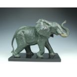 A modern patinated metal elephant sculpture, bronze-style, on a stone base, 10in. (25.5cm.) high.