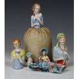 A collection of porcelain pin cushion top dolls, dating from the 1920s onwards, varying sizes, one