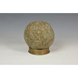 A 17th / 18th century carved granite cannonball, 20in. diameter, raised on brass shell case.