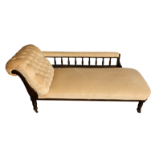 A late Victorian ebonised chaise longue, the buttoned beige velour upholstery, spindle turned