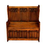 A carved oak 17th century style monks bench, first half 20th century, with three gothic style