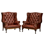 A pair of red button back leather wingback library armchairs, mid-20th century, the camel backs,