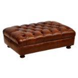 A matching buttoned brown leather rectangular footstool, raised on turned and stained beechwood