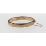 A hollow 9ct rose gold hinged bangle, with engraved floral and foliate detailing to the front