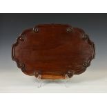 A George III oval mahogany tray, of shaped form, having dished pie crust and swirl moulded edge,