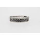 A 14ct white gold, white and black diamond three row ring, the row of eleven round cut black