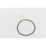 A 9ct gold and tanzanite line bracelet, the oval cut tanzanites of pale lavender colouring and