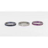 A trio of platinum eternity bands, one set with calibre cut sapphires, ring size R, one set with