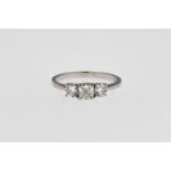 An 18ct white gold and diamond trilogy ring, the central cushion cut diamond weighing