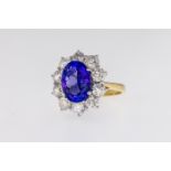 An 18ct gold, tanzanite and diamond cluster ring, the central, oval cut tanzanite weighing