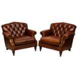 A matching pair of button back brown leather library style armchairs, raised on turned and stained