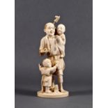 A Japanese carved ivory okimono of a father and children, Meiji period (1868-1912), the man standing
